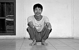 Phongsavath hockt lächelnd auf dem Boden.
